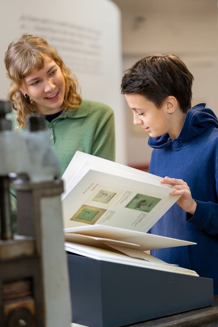 Besuchende blättern in einem Buch mit Janssen-Werken. Foto: Studio 3x3