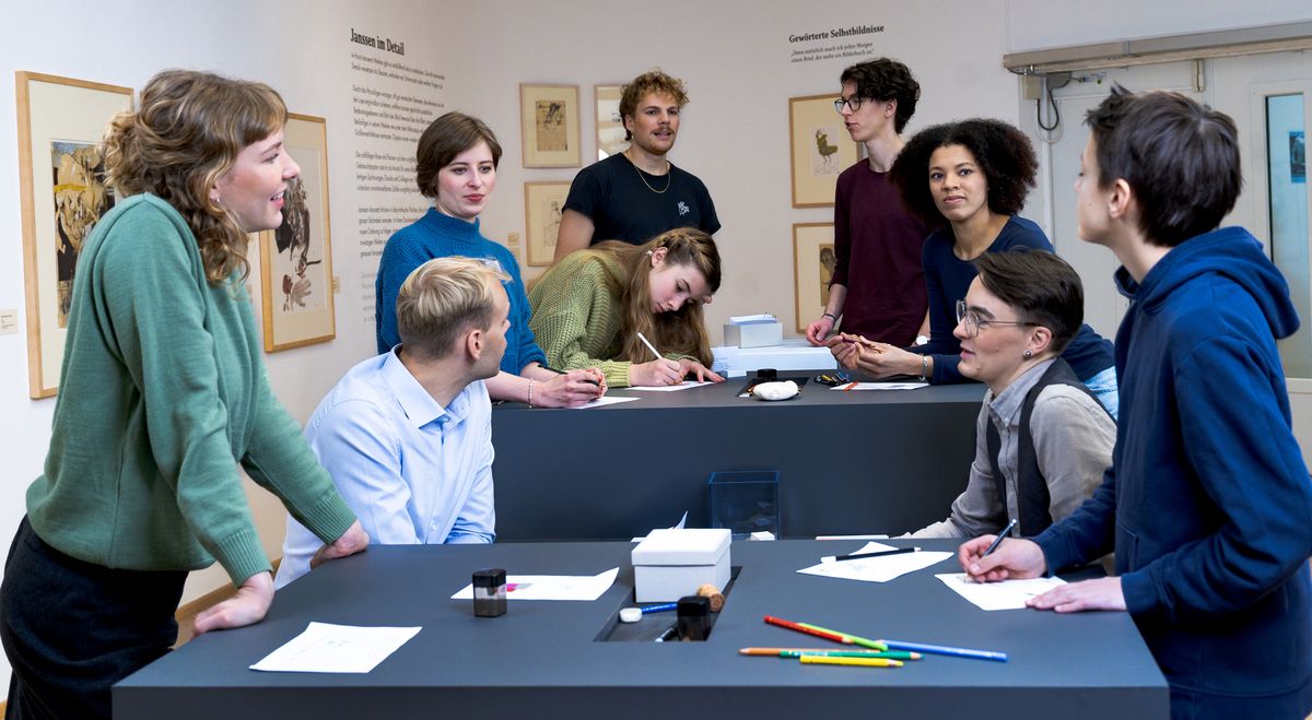 Besucher/innen am Zeichentisch in der Janssen-Ausstellung. Foto: Studio 3x3