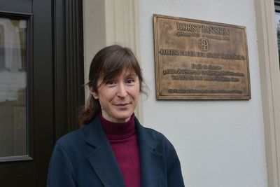 Stipendiatin Aline Helmcke vor dem Haus in der Lerchenstraße, neben ihr die Plakette des Ehrenbürgers Horst Janssen. Foto: Horst-Janssen-Museum
