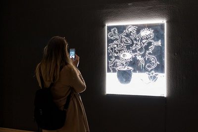 Besucherin vor einem leuchtenden Bild von Tobias Dostal. Foto: Christian J. Ahlers